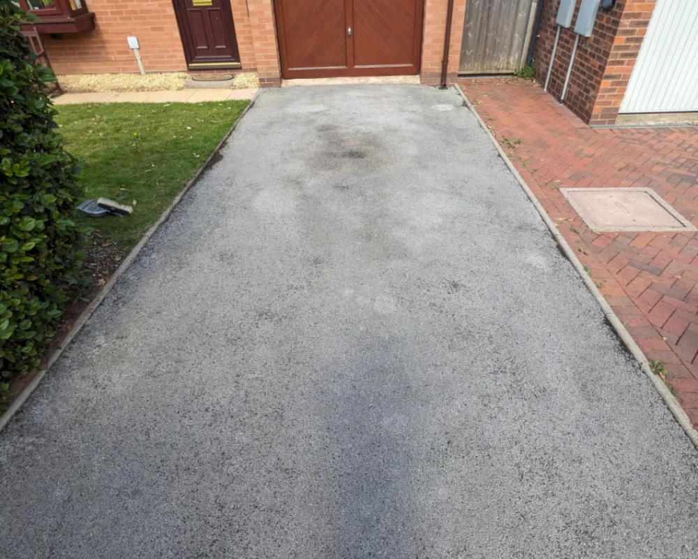 Faded grey tarmac driveway before SmartGuard recolouring and sealing.