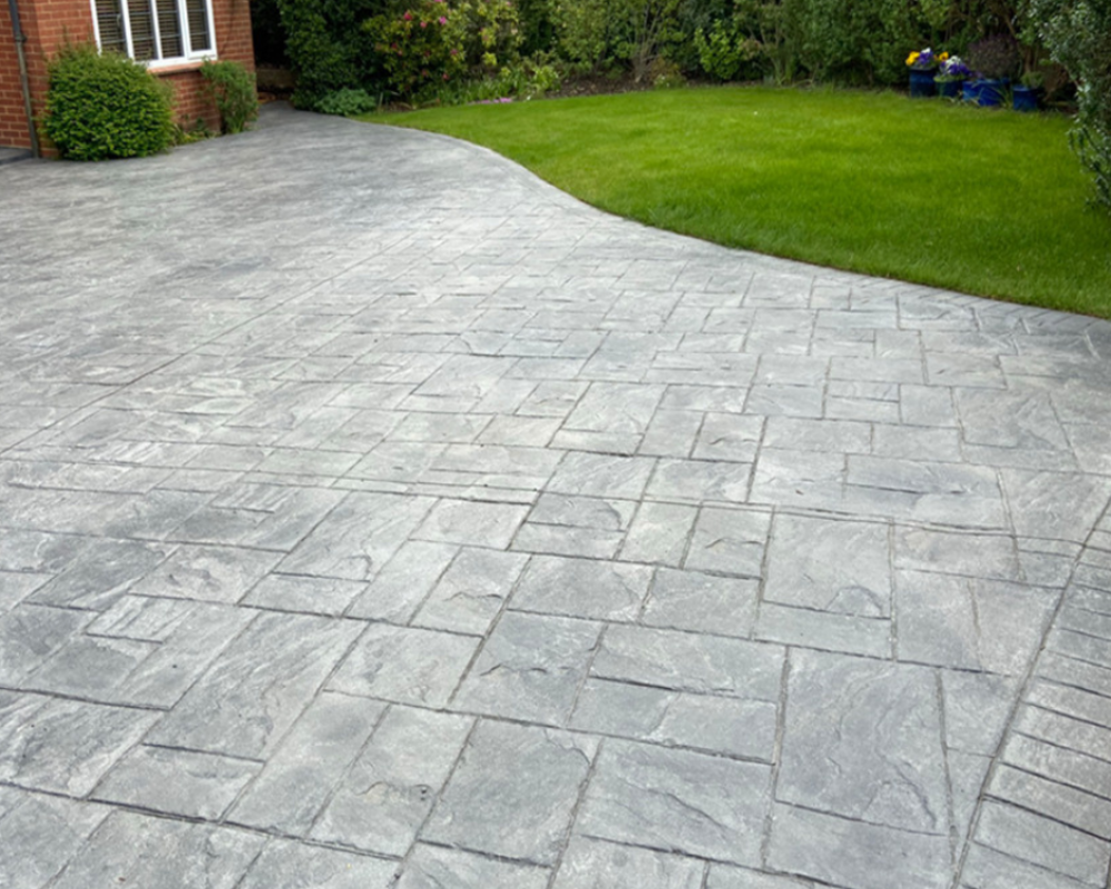 Imprinted concrete driveway before SmartGuard cleaning, appearing faded and weathered.