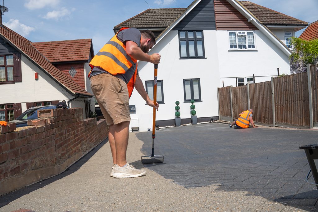 SmartGuard technician applying protective coating to a residential tarmac driveway — professional driveway restoration and exterior cleaning services