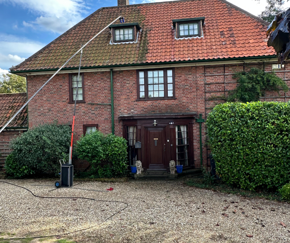 roof cleaning in progress on a residential property using a long-reach cleaning lance